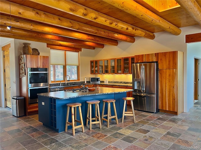 kitchen featuring dark tile floors, a kitchen island, stainless steel appliances, a breakfast bar area, and wood ceiling