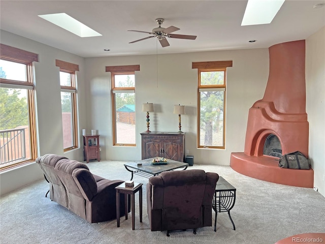 carpeted living room with a wealth of natural light, ceiling fan, and a skylight