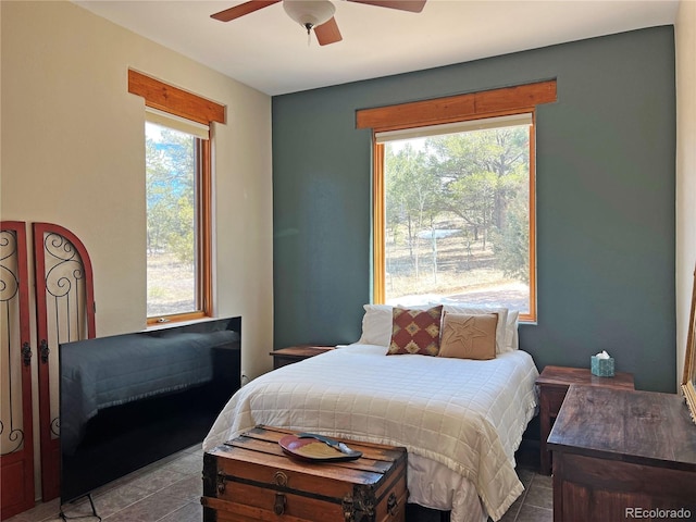 bedroom with dark tile flooring, ceiling fan, and multiple windows