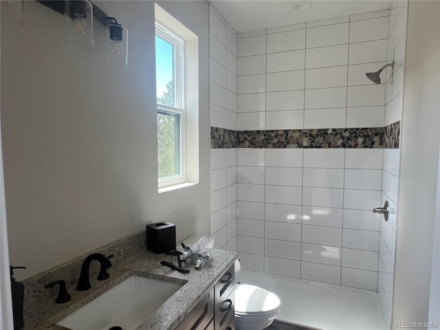 bathroom featuring tiled shower, vanity, and toilet