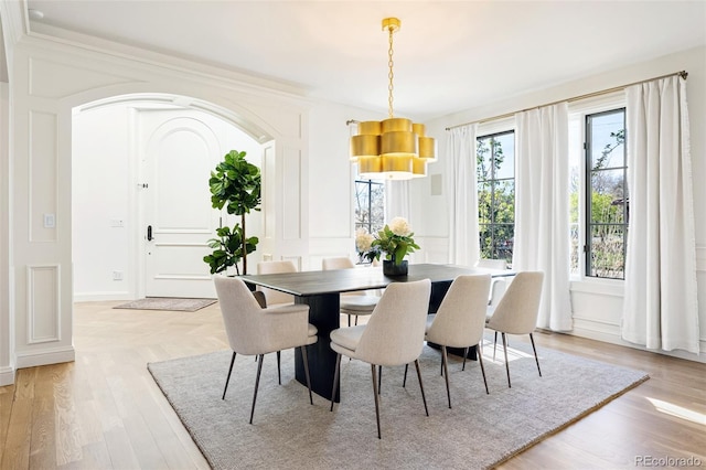 dining area featuring light wood-type flooring and a decorative wall