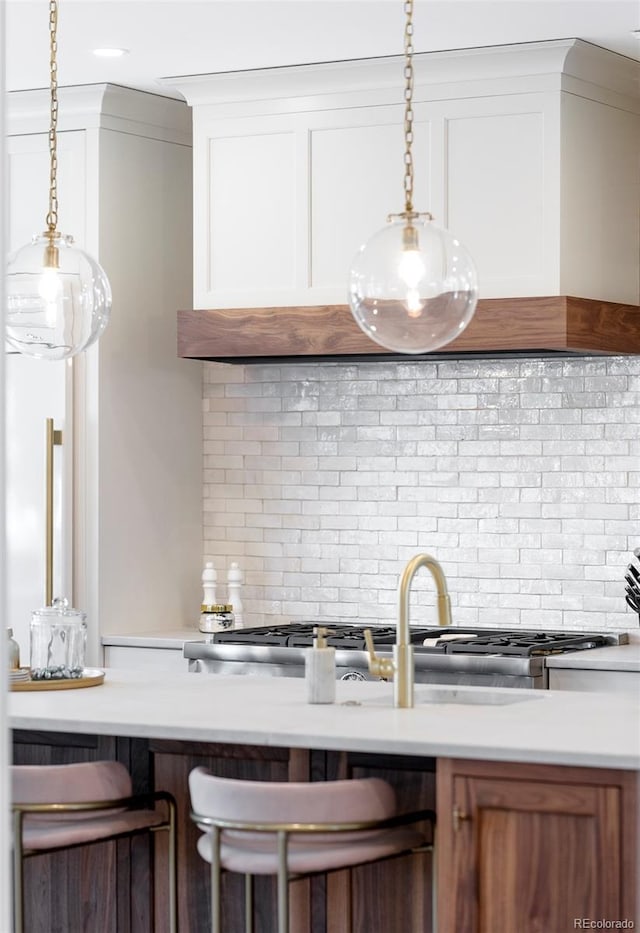 kitchen featuring white cabinetry, tasteful backsplash, light countertops, and hanging light fixtures
