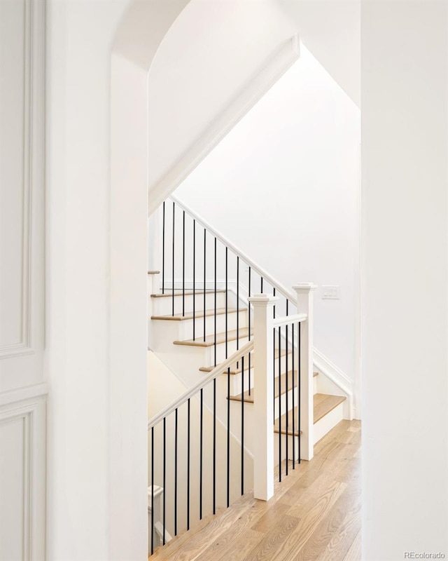 stairs with arched walkways and wood finished floors