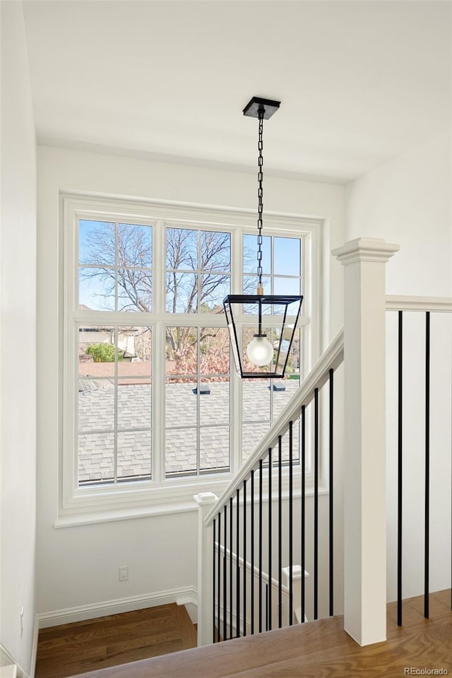 staircase with a wealth of natural light, wood finished floors, and baseboards