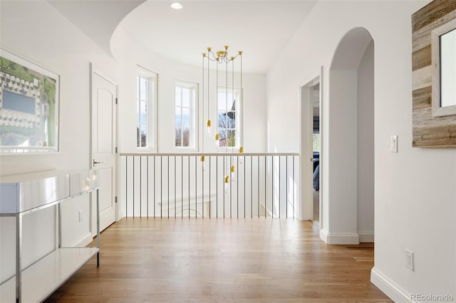interior space with plenty of natural light, wood finished floors, baseboards, and arched walkways