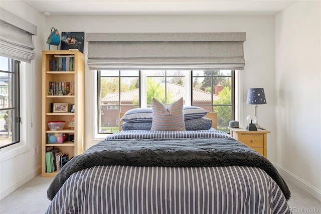 bedroom featuring baseboards, multiple windows, and carpet