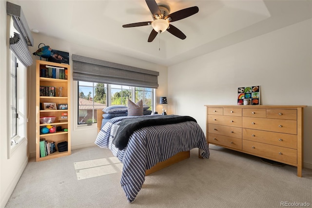 bedroom with a tray ceiling, ceiling fan, and light carpet