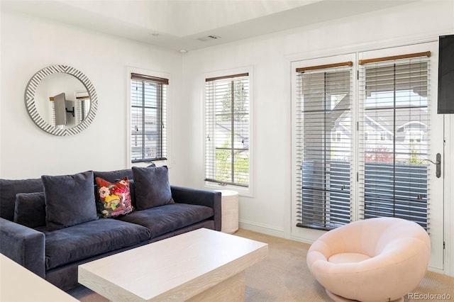 living room with baseboards, a wealth of natural light, light carpet, and visible vents