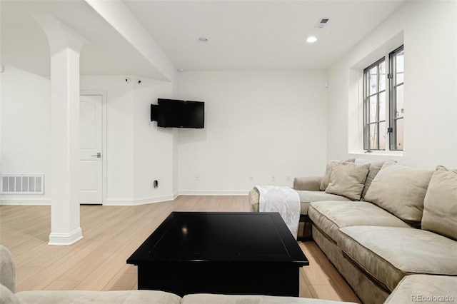 living room with light wood-type flooring, visible vents, and baseboards