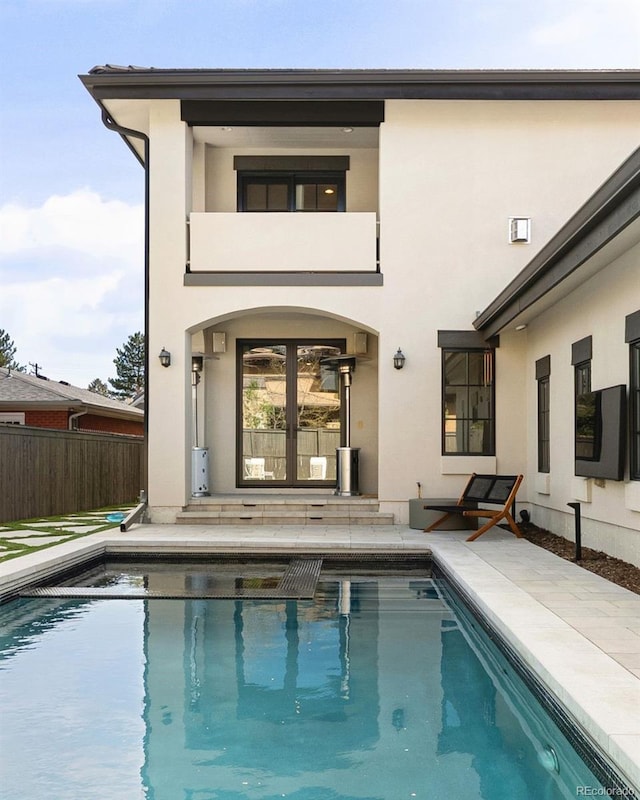 back of house featuring french doors, stucco siding, fence, and a fenced in pool