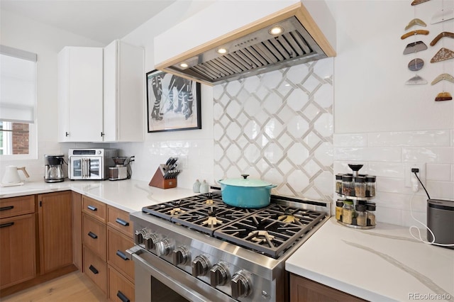 7079 S Locust Pl, Centennial, CO 80112 - kitchen featuring backsplash, high end stainless steel range oven, brown cabinets, white cabinets, and custom range hood