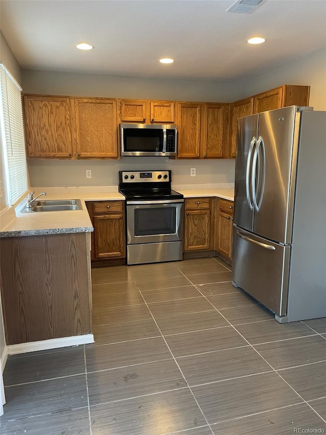 kitchen with stainless steel appliances, dark tile patterned flooring, and sink