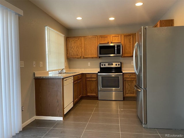 kitchen with sink, dark tile patterned floors, and appliances with stainless steel finishes