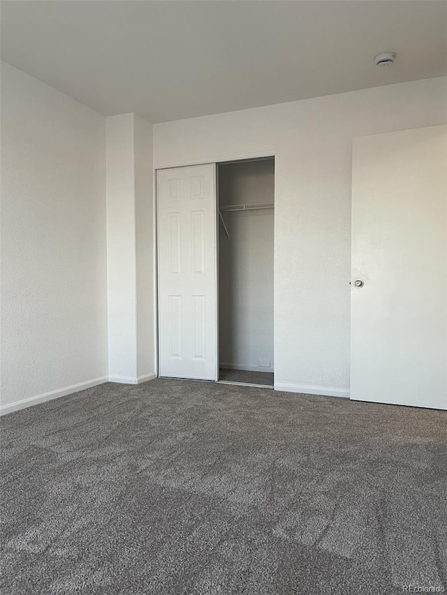 unfurnished bedroom with a closet and dark colored carpet