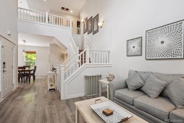 10955 Dearborne Dr, Parker, CO 80134 - living area featuring radiator heating unit, wood finished floors, stairway, a high ceiling, and arched walkways