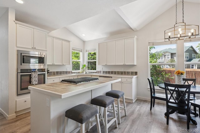 10955 Dearborne Dr, Parker, CO 80134 - kitchen featuring appliances with stainless steel finishes, lofted ceiling, tile countertops, light wood finished floors, and white cabinets