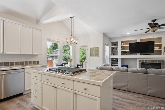 10955 Dearborne Dr, Parker, CO 80134 - kitchen with stainless steel appliances, tile counters, vaulted ceiling, light wood-style flooring, and white cabinetry