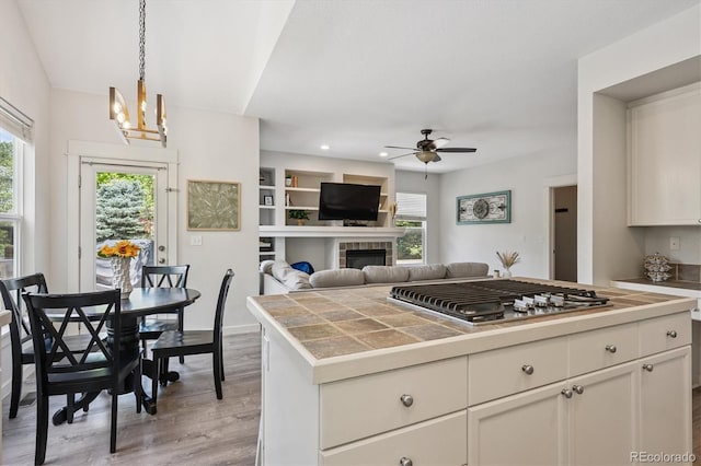 10955 Dearborne Dr, Parker, CO 80134 - kitchen featuring stainless steel gas stovetop, ceiling fan, a chandelier, light wood finished floors, and white cabinets