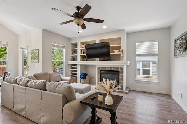 10955 Dearborne Dr, Parker, CO 80134 - living room featuring ceiling fan, wood finished floors, a tile fireplace, recessed lighting, and built in features