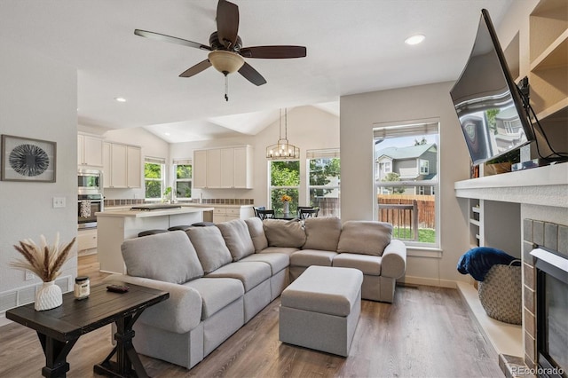 10955 Dearborne Dr, Parker, CO 80134 - living room with a chandelier, wood finished floors, a glass covered fireplace, vaulted ceiling, and a ceiling fan