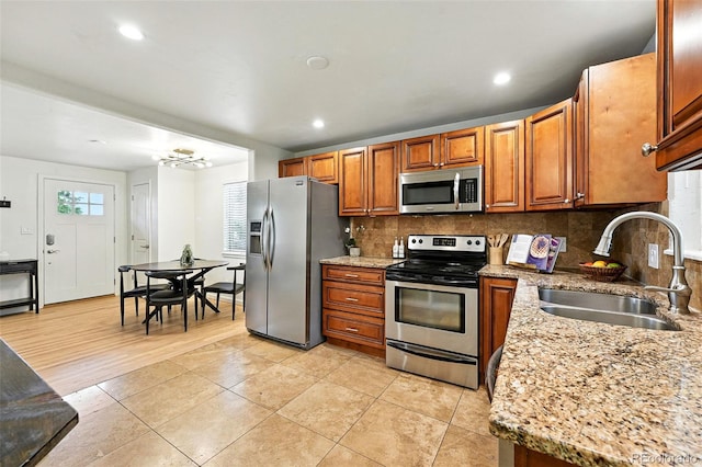 2025 Otis St, Edgewater, CO 80214 - kitchen with appliances with stainless steel finishes, tasteful backsplash, brown cabinets, light tile patterned floors, and recessed lighting