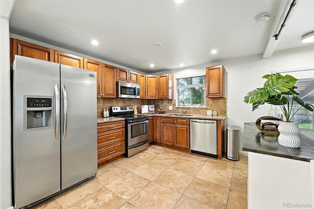 2025 Otis St, Edgewater, CO 80214 - kitchen featuring appliances with stainless steel finishes, decorative backsplash, brown cabinetry, light stone counters, and recessed lighting