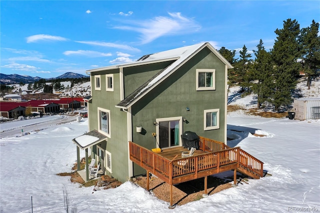 snow covered property with a deck with mountain view