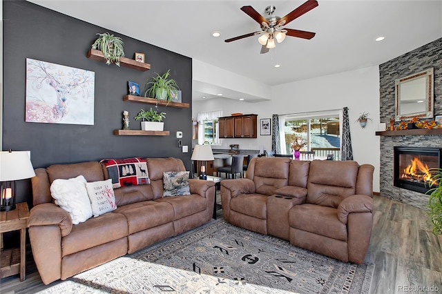 living room with a fireplace, ceiling fan, and light hardwood / wood-style flooring