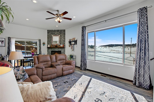 living room with ceiling fan, a stone fireplace, and dark hardwood / wood-style flooring