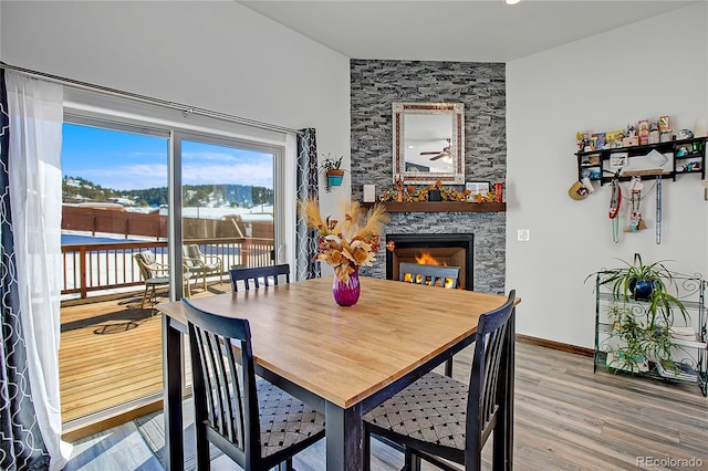 dining area with hardwood / wood-style flooring and a stone fireplace