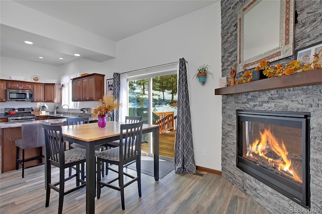 dining room featuring light hardwood / wood-style floors, a stone fireplace, and sink