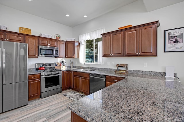 kitchen with light wood-type flooring, stainless steel appliances, kitchen peninsula, and sink