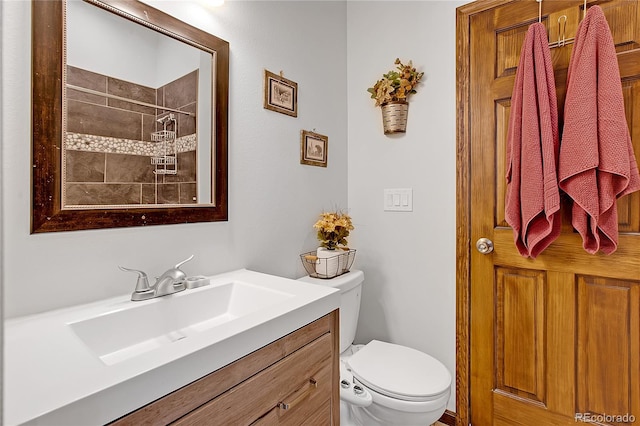 bathroom with tiled shower, vanity, and toilet