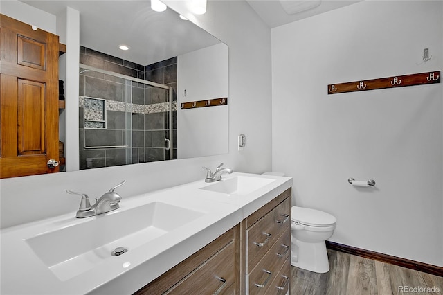 bathroom featuring hardwood / wood-style flooring, a shower with door, vanity, and toilet