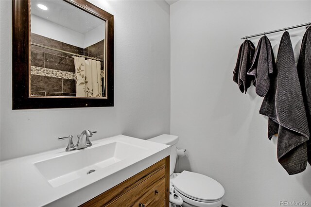 bathroom with curtained shower, vanity, and toilet