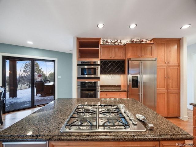 kitchen with dark stone countertops, light hardwood / wood-style floors, and appliances with stainless steel finishes