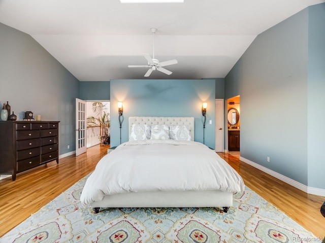 bedroom with hardwood / wood-style floors, vaulted ceiling, ceiling fan, and ensuite bathroom