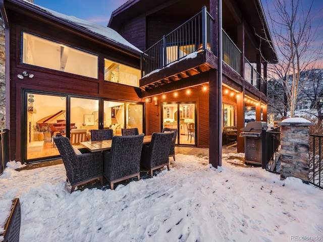 snow covered back of property featuring a balcony