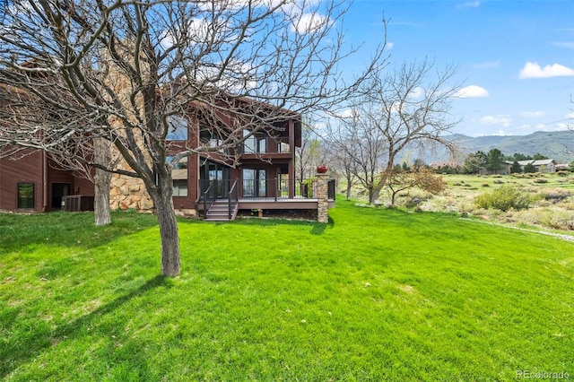 view of yard with cooling unit, a deck with mountain view, and a balcony