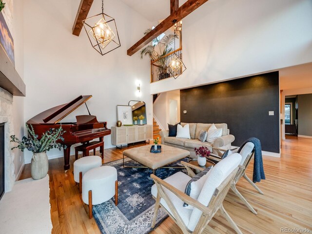 living area with an inviting chandelier, stairs, a towering ceiling, wood finished floors, and beamed ceiling