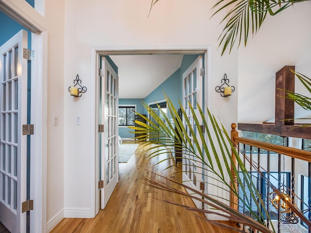 hallway featuring baseboards, french doors, and wood finished floors