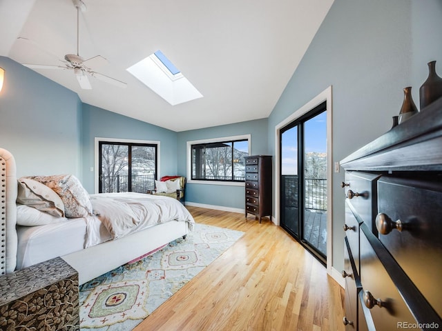 bedroom featuring a ceiling fan, light wood-style flooring, baseboards, vaulted ceiling with skylight, and access to exterior