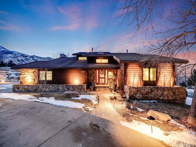 view of front of property with stone siding, a mountain view, and a chimney