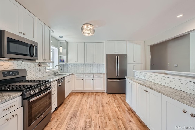 kitchen featuring light stone countertops, sink, white cabinetry, and stainless steel appliances