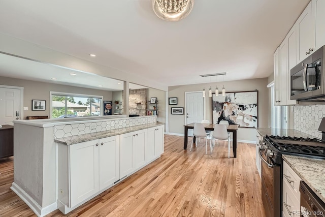 kitchen featuring white cabinets, appliances with stainless steel finishes, decorative backsplash, and pendant lighting