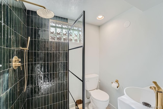 bathroom featuring toilet and a tile shower