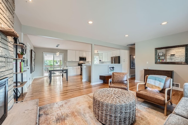 living room with a stone fireplace and light hardwood / wood-style floors