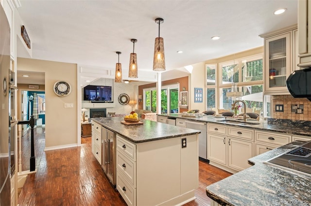 kitchen with a kitchen island, pendant lighting, dishwasher, sink, and backsplash