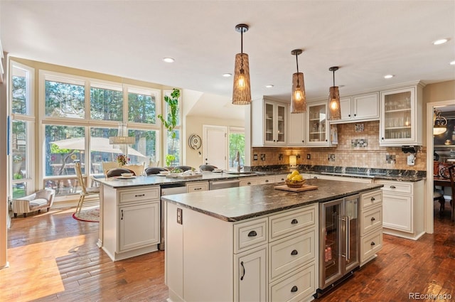 kitchen featuring wine cooler, decorative light fixtures, kitchen peninsula, and a kitchen island