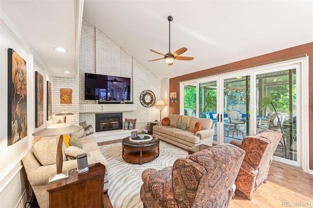 living room with french doors, lofted ceiling, light wood-type flooring, ceiling fan, and a fireplace